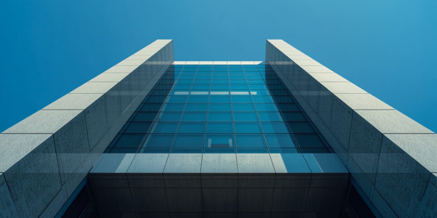 Upward view of a modern glass and stone office building against a clear blue sky